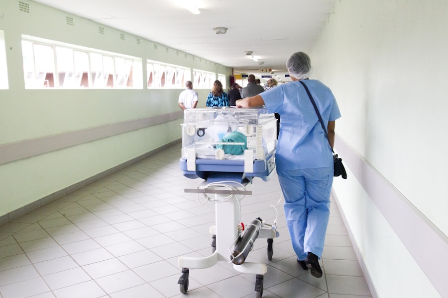 Nurse moving equipment along a hospital ward corridor